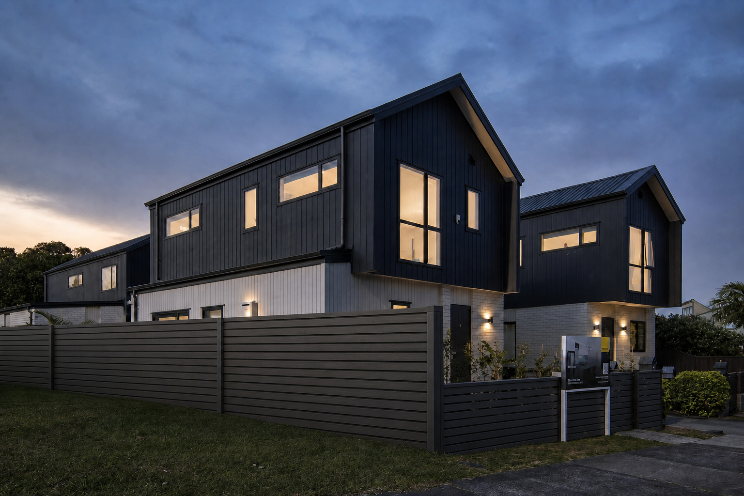 Side exterior view of Stonefield Residence showing dark cladding, pale masonry and privacy fencing.